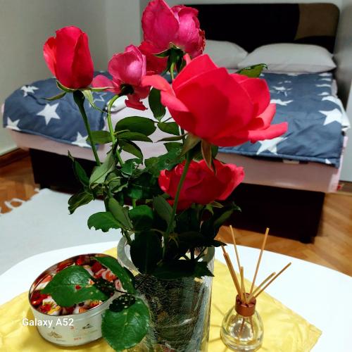 a vase with flowers on a table next to a bed at Apartman PAVLE in Plužine