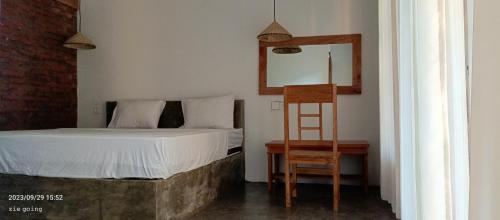 een slaapkamer met een bed, een stoel en een spiegel bij Mengalung Bungalow in Kuta Lombok