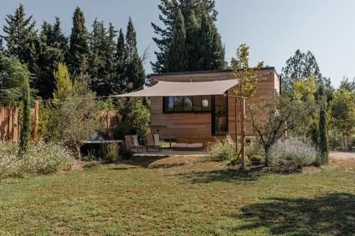 une petite maison avec un grand parasol dans une cour dans l'établissement L'Atelier Tiny House Provence, à Châteaurenard