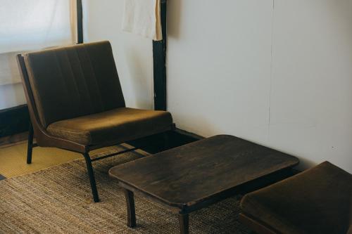 a chair and a coffee table in a room at Hostel Saruya in Fujiyoshida