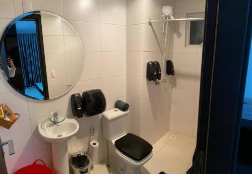 a bathroom with a sink and a toilet and a mirror at Baln Piçarras-Bally Beach Club Beira Mar in Piçarras
