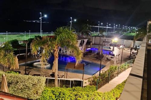 a pool at night with palm trees and lights at Baln Piçarras-Bally Beach Club Beira Mar in Piçarras