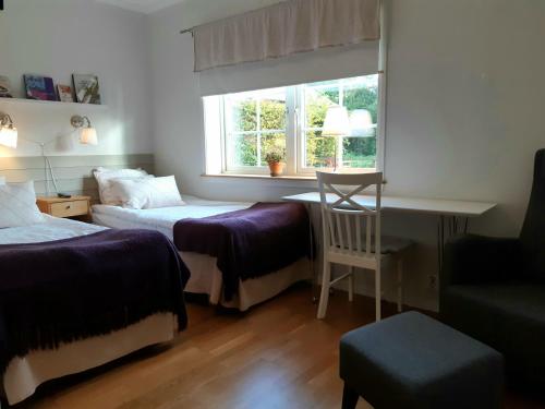 1 Schlafzimmer mit 2 Betten, einem Schreibtisch und einem Fenster in der Unterkunft Närebo Gårdshotell & Restaurang in Lidköping