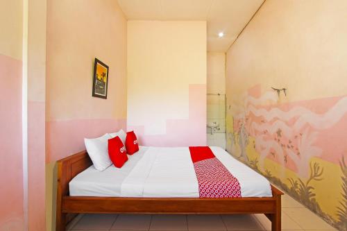 a bedroom with a bed with red pillows and a shower at Super OYO 3693 Kopi Klotok Homestay Syariah in Magelang