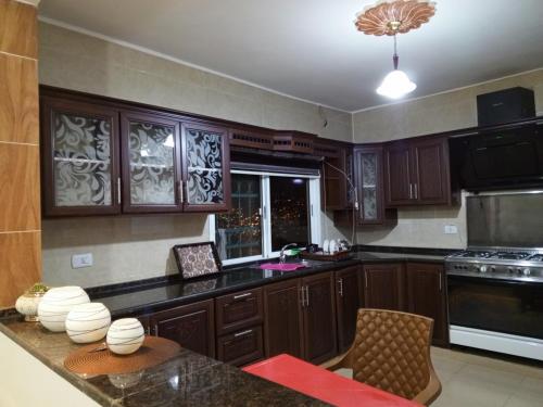 eine große Küche mit Holzschränken und einem Tisch in der Unterkunft Petra Inn House in Wadi Musa