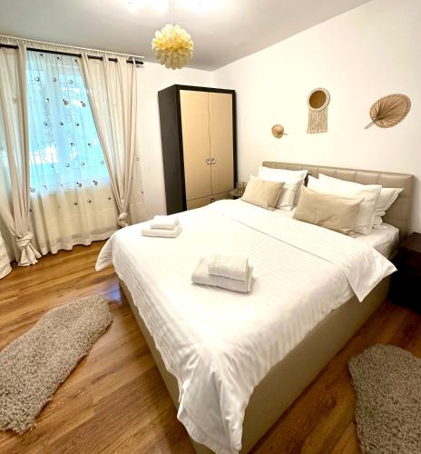 a bedroom with a large white bed with two towels on it at Scandinavia Apartament in Piatra Neamţ