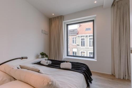 a bedroom with a bed and a large window at Margriet Apart-Suites in Ghent