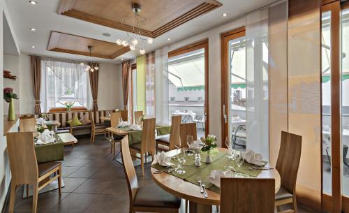 un restaurante con mesas, sillas y ventanas en Hotel Pfandleralm, en San Martino