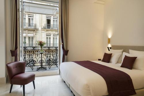 1 dormitorio con cama, ventana y silla en Vestay Montaigne, en París
