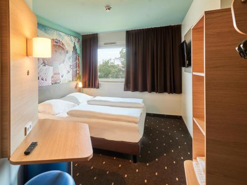 una camera d'albergo con due letti e un tavolo di B&B Hotel Darmstadt a Darmstadt