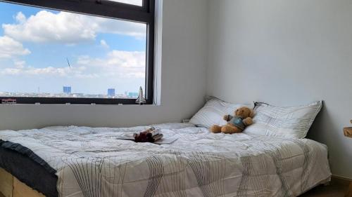 two teddy bears sitting on a bed with a window at Bcons Garden Luxury Aparment in Dĩ An