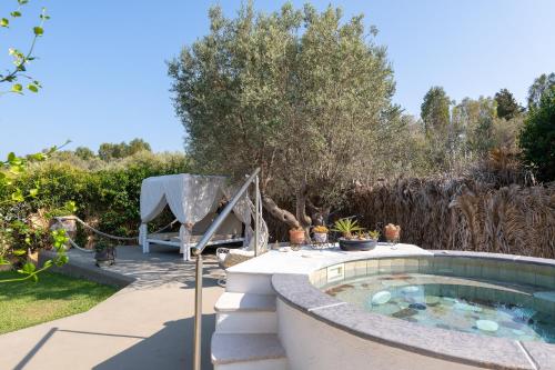 a pool in a garden with a table and a chair at Elefteria Apts & Suites in Kolimbia