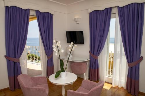 a living room with purple curtains and a table and chairs at Hotel Marincanto in Positano