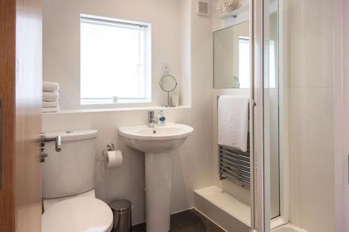 a white bathroom with a toilet and a sink at Clearwater 82, Primrose Bank in Somerford Keynes