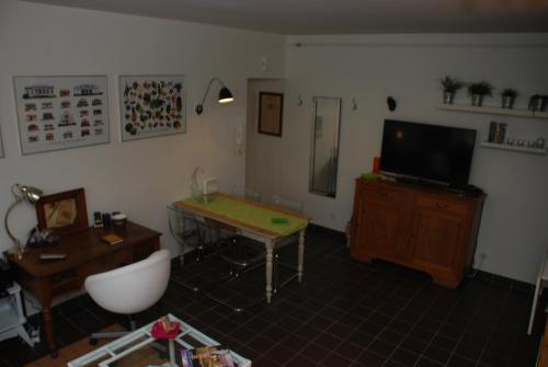a living room with a table and a television at Logis Varennes in Gravelines