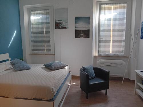 1 dormitorio con 1 cama, 1 silla y 2 ventanas en Via Guido Panciroli il guscio, en Reggio Emilia