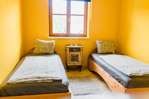 two beds in a yellow room with a window at Tauglerei Appartement Enzian in den Zauberbergen in Sankt Koloman