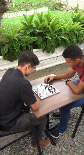 two boys playing a game of chess at a table at DeRequka Hostel in Pereira
