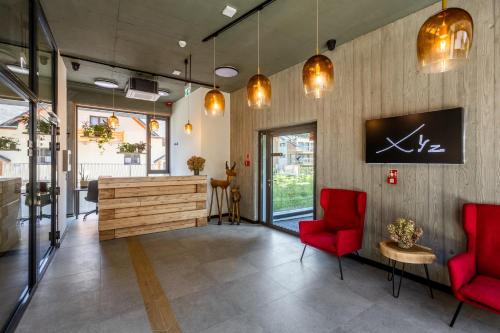 a lobby with red chairs and a reception desk at XYZ eXtreme You Zen in Szczyrk
