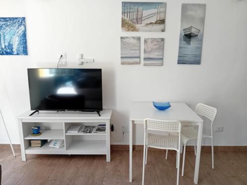 a living room with a tv and a white table and chairs at Via Guido Panciroli il guscio in Reggio Emilia