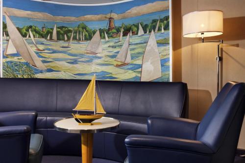 a living room with a couch and a painting of sailboats at ss Rotterdam by WestCord in Rotterdam