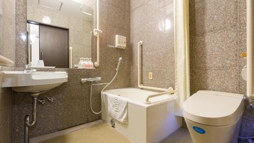 a bathroom with a sink and a tub and a toilet at Toyoko Inn Shin takaoka eki Shinkansen Minami guchi in Takaoka