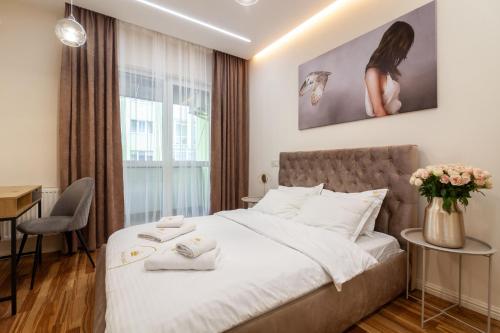 a bedroom with a bed and a table with flowers at Royal 2 apartments on Shevchenka str in Lviv