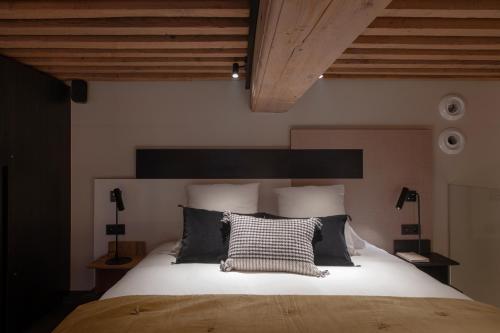 a bedroom with a large bed with black and white pillows at MiHotel Serlin in Lyon