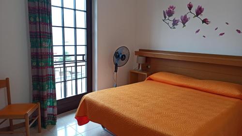 Piccolo Residence في مالسيسيني: غرفة نوم بسرير ومروحة ونافذة