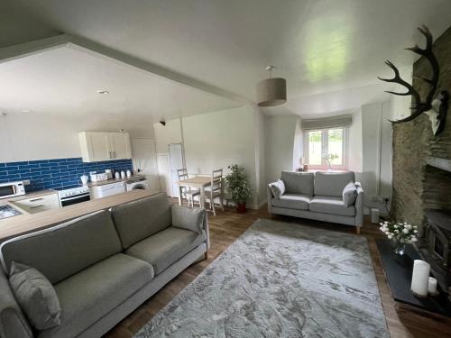 sala de estar con sofá y cocina en Winstitchen Cottage, en Simonsbath