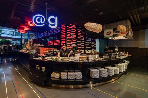 a bar in a restaurant with people preparing food at Galleria Sukhumvit 10 Bangkok by Compass Hospitality in Bangkok