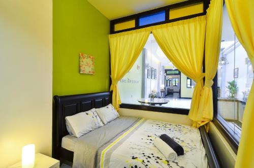 1 dormitorio con 1 cama con cortinas amarillas y ventana en The Egerton Melaka en Melaka