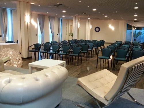 una habitación con un montón de sillas y un sofá blanco en Janus Hotel Fabriano, en Fabriano