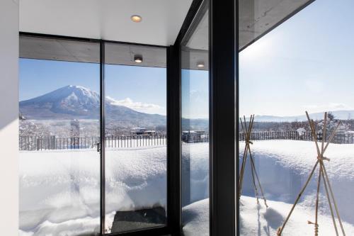 倶知安町にあるDharma Niseko(ダーマニセコ)の窓越しに雪山を望む