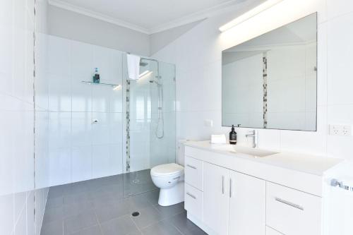 a white bathroom with a shower and a toilet at Absolute Waterfront Lakehouse Fishing Point Waterfront Pool Jetty in Fishing Point