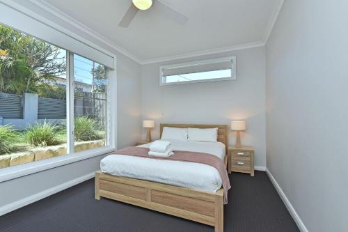 a bedroom with a bed and a large window at Absolute Waterfront Lakehouse Fishing Point Waterfront Pool Jetty in Fishing Point