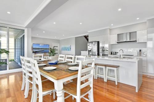a kitchen and dining room with a wooden table and chairs at Absolute Waterfront Lakehouse Fishing Point Waterfront Pool Jetty in Fishing Point