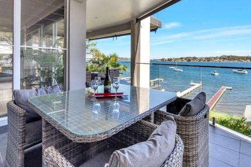 a glass table on a balcony with a view of the water at Absolute Waterfront Lakehouse Fishing Point Waterfront Pool Jetty in Fishing Point