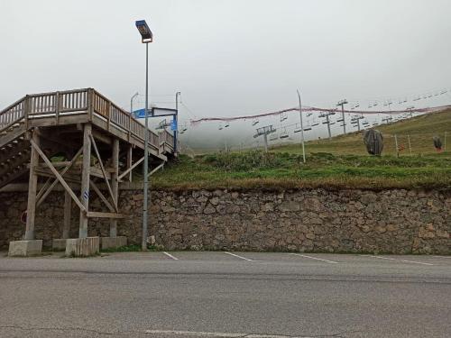 un pont en bois sur un mur de pierre à côté d'une route dans l'établissement Apartamento Pla d'adet Saint Lary, à Saint-Lary-Soulan