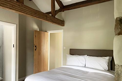 a bedroom with a white bed and a wooden ceiling at Croft House Cottage in Halifax