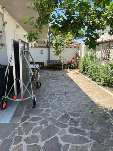 a stone walkway with a cart in a yard at Villino con giardino a 10 minuti a piedi dal mare e vicino a Roma in Torvaianica