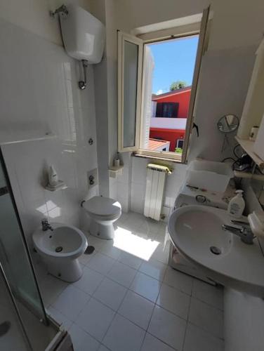 a white bathroom with a toilet and a sink at Villino con giardino a 10 minuti a piedi dal mare e vicino a Roma in Torvaianica