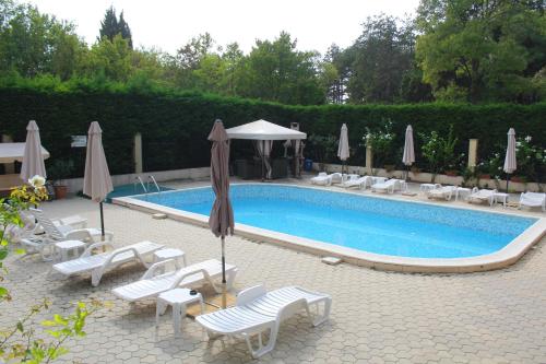 una piscina con sedie a sdraio e ombrelloni accanto ad essa di Lovely 1-bedroom apartment with pool, 250 m to the beach a Pomorie