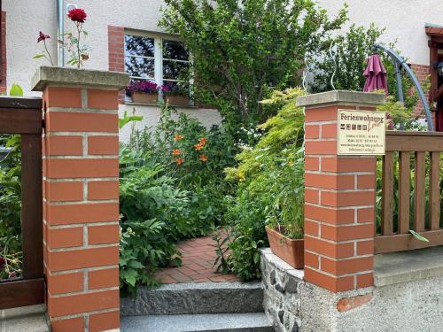a brick post with a sign in front of a garden at Ferienwohnung Lotte am Tennisplatz in Görlitz