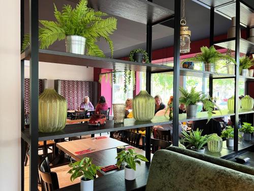 a restaurant with tables and potted plants on shelves at Hotel Da Toni in Neuenkirchen