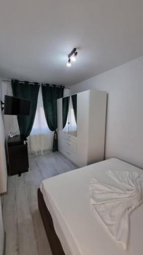 a white bed in a bedroom with green curtains at vApartament central in Hunedoara