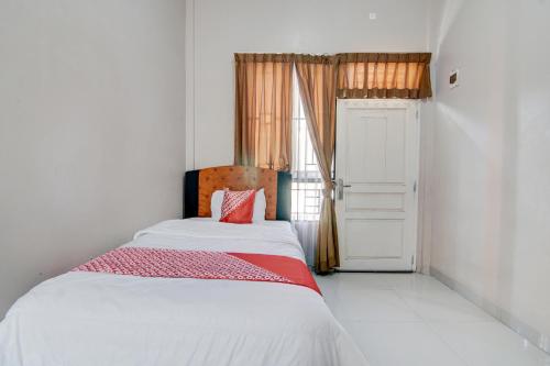 um quarto com uma cama com um cobertor vermelho e branco em OYO 92806 Penginapan Geby Syariah em Pekanbaru