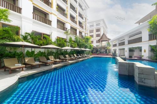 a swimming pool with chairs and umbrellas next to a building at Angkor Land Urban Boutique in Siem Reap