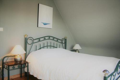 um quarto com uma cama branca e uma mesa com candeeiros em Albatros D2 em De Haan