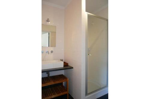 een badkamer met een glazen douche en een wastafel bij Green Garden XV 0004 in De Haan